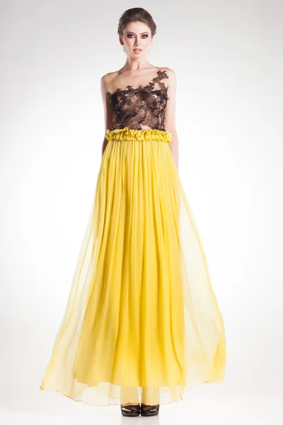 스튜디오에서 검은 레이스 긴 노란색 드레스를 입고 포즈를 취하는 아름 다운 여자 모델 — 스톡 사진