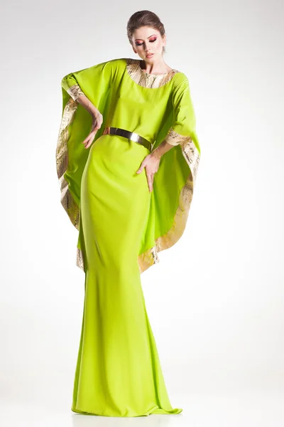 Modelo bela mulher posando em ouro elegante e vestido verde no estúdio — Fotografia de Stock
