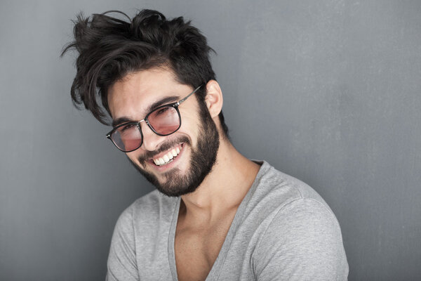 Сексуальный мужчина с бородой, широко улыбающийся к стене
