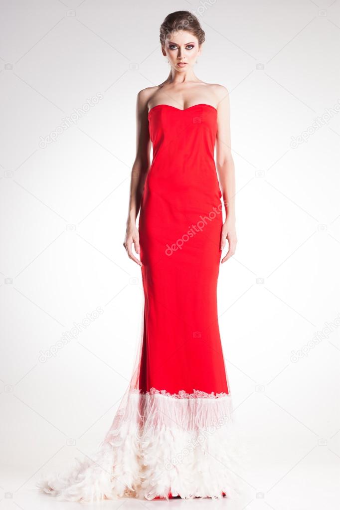Beautiful woman model posing in elegant red dress in the studio