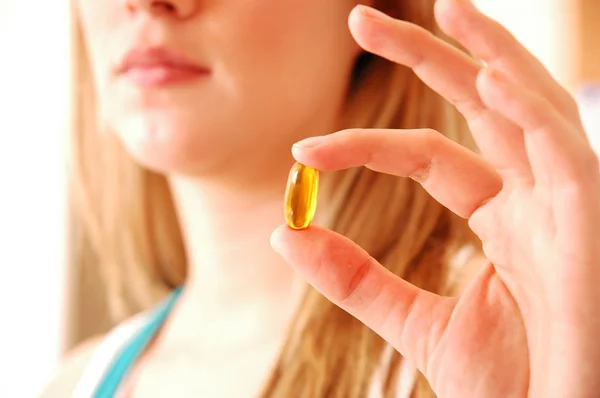 sarışın bir kadın tutarak vitamini kapsülü