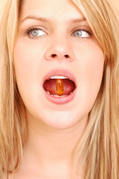 Blond kvinna med vitamin i munnen Stockbild