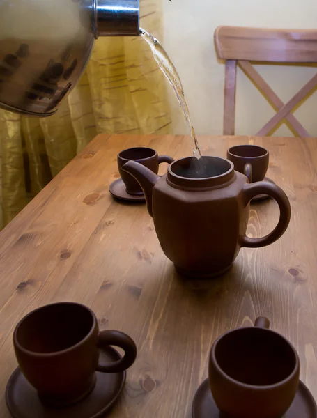 Gliny czajnik i filiżanki na drewnianym stołem — Zdjęcie stockowe