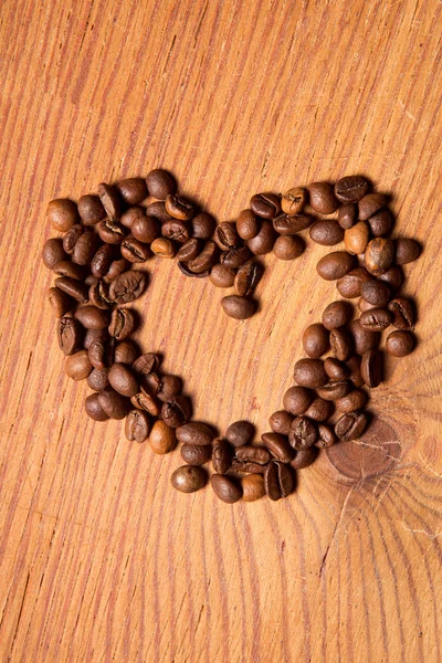 Coffee beans in the form of heart on a wooden table — Stock Photo, Image