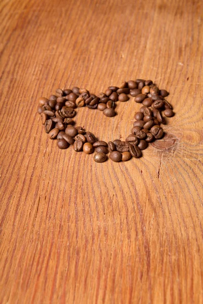 Coffee beans in the form of heart on a wooden table — Stock Photo, Image