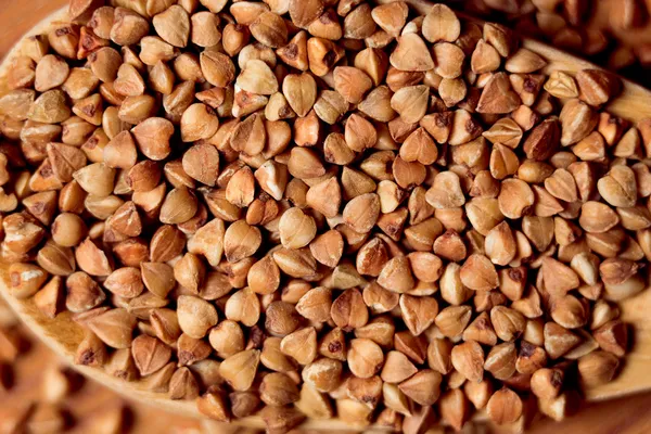 Buckwheat groats and wooden spoon — Stock Photo, Image