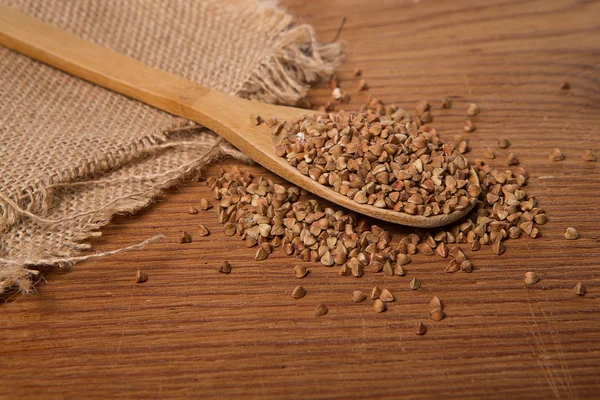 Buckwheat groats and wooden spoon — Stock Photo, Image