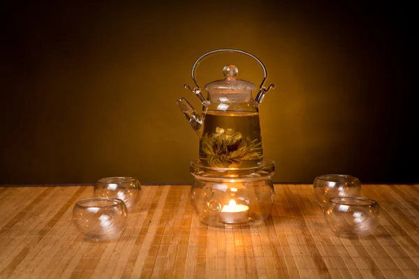 Glas theepot met exotische groene thee op houten tafel op bruine achtergrond — Stockfoto