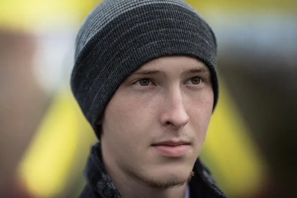 Les hommes hiver mode. Beau homme aux cheveux bruns portant une écharpe grise, un chapeau en laine grise, des gants en laine grise et un manteau gris. Recouvert de neige. Froid. Un look décontracté. Studio tourné isolé sur fond gris . — Photo