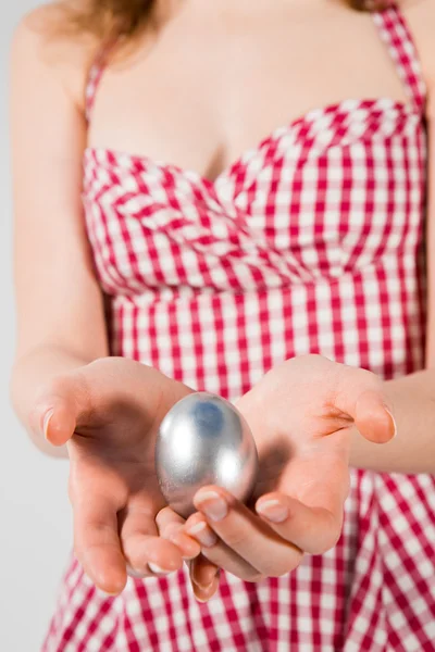 Mãos bem cuidadas de uma jovem mulher em uma camisa amarela segurando um ovo . — Fotografia de Stock