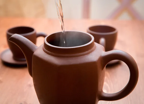 Bule de barro e xícaras em uma mesa de madeira — Fotografia de Stock