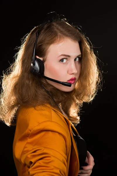 Joven hermosa mujer-operador con sonrisas auriculares, está aislado sobre fondo negro . —  Fotos de Stock