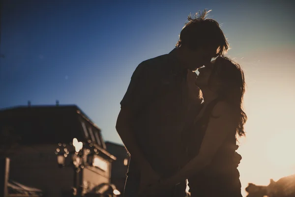 Gli amanti romantici che si abbracciano al crepuscolo con il tramonto sullo sfondo — Foto Stock