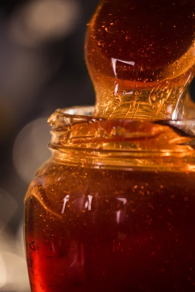 Honig tropft aus einem hölzernen Honigwagen auf schwarzem Hintergrund — Stockfoto