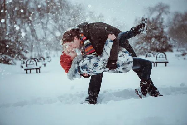 Jovem casal feliz no Parque de Inverno se divertindo. Família ao ar livre. beijo de amor — Fotografia de Stock