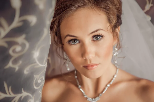 Bella Sposa illuminata dalla luce del sole da una finestra. bella giovane sposa in piedi accanto a una grande finestra — Foto Stock