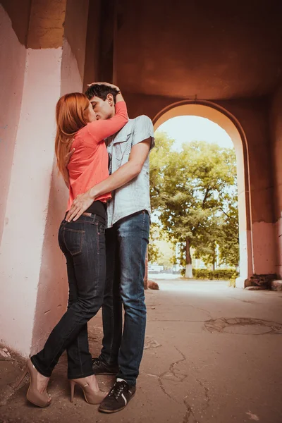 Unga par förälskade. De kysser varandra. Vinterskog och gamla båge som bakgrund. — Stockfoto