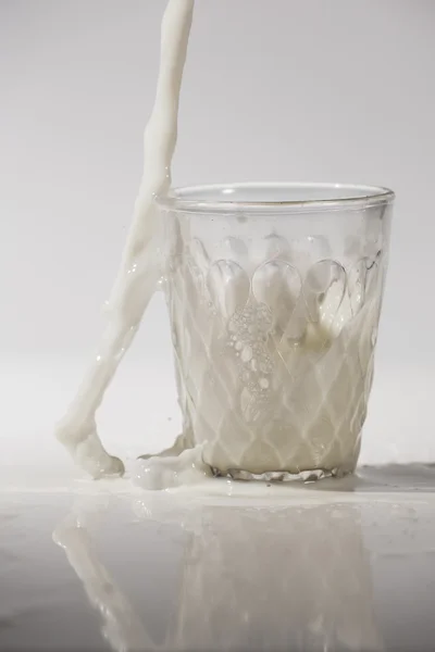 Verter la leche en un vaso aislado sobre fondo blanco — Foto de Stock