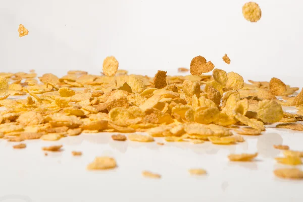 Flocos de milho caindo em uma pilha, sobre fundo branco — Fotografia de Stock