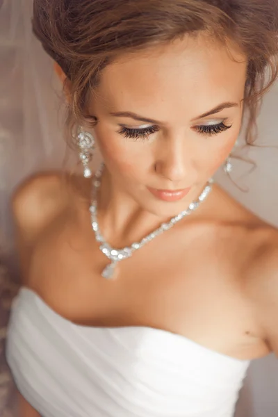 Beautiful Bride lit by sunlight from a window. beautiful young bride standing beside a large window Stock Photo