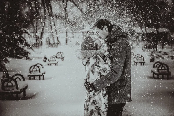 Young couple kissing on snow. Black and white. — Stock Photo, Image