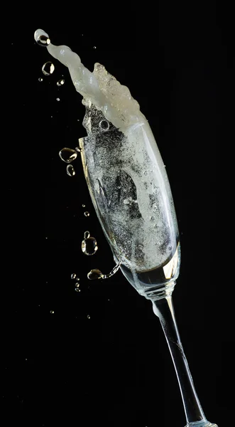 Glass of champagne with splash, isolated on black background — Stock Photo, Image