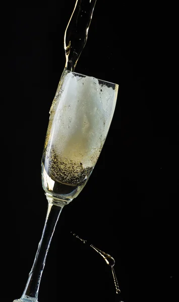 Glass of champagne with splash, isolated on black background — Stock Photo, Image