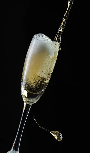 Glass of champagne with splash, isolated on black background — Stock Photo, Image