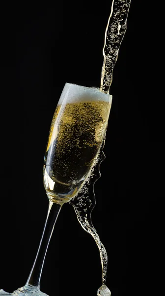 Glass of champagne with splash, isolated on black background — Stock Photo, Image