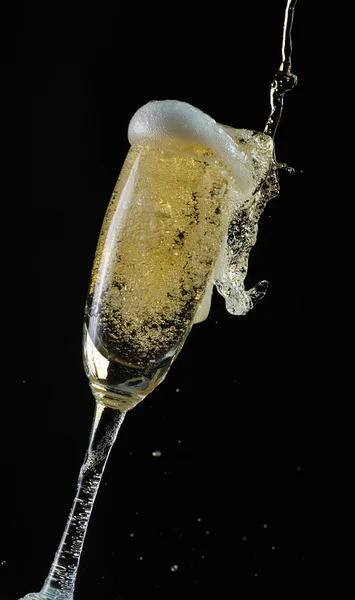 Glass of champagne with splash, isolated on black background — Stock Photo, Image