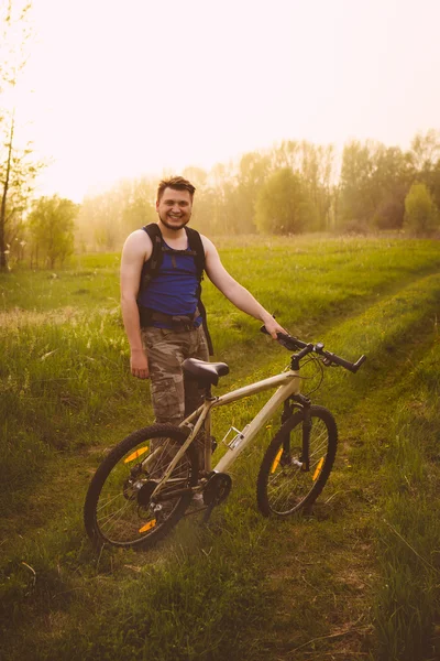 Jeune homme beau posant sur la prairie verte avec vélo vintage — Photo