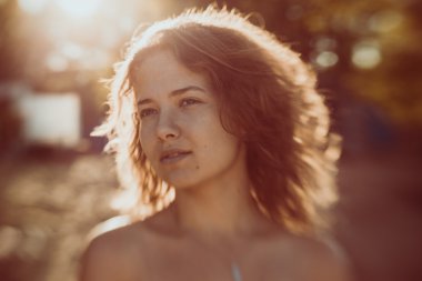 Doğada yeşil ağacın yanında poz veren genç seksi kadının güzel yüzü.