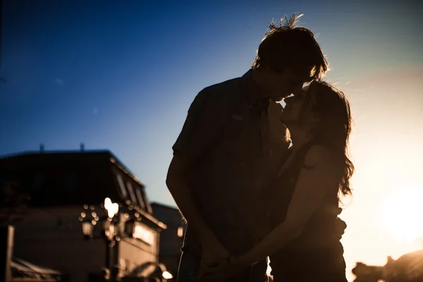 Unga par kysser över solnedgången — Stockfoto