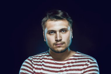 çizgili tshirt siyah arka plan karşı arayan genç adam gülümsüyor