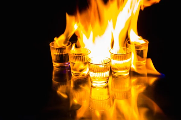 Glasses with burning alcohol on black background — Stock Photo, Image