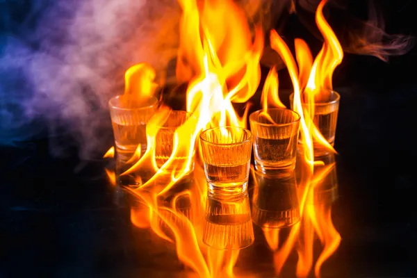 Óculos com álcool em chamas no fundo preto — Fotografia de Stock