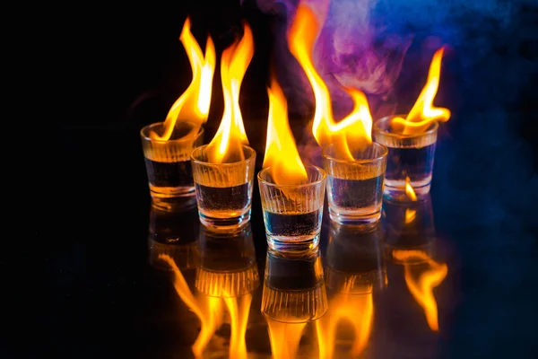 Glasses with burning alcohol on black background — Stock Photo, Image