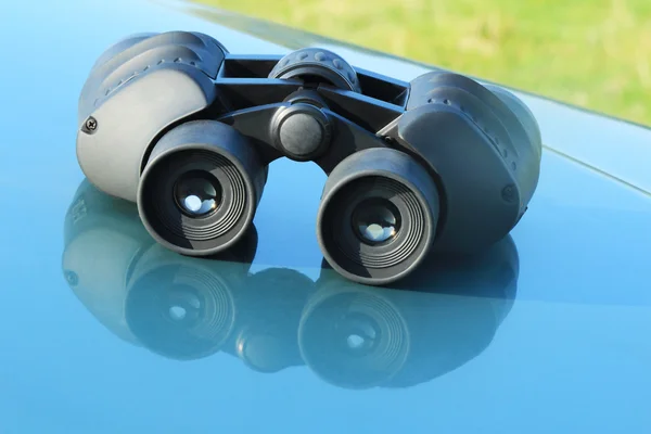 Binoculars lying on the car hood. — Stock Photo, Image