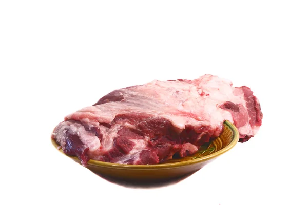 Un gran trozo de carne de cerdo cruda en plato de cerámica sobre un fondo blanco — Foto de Stock