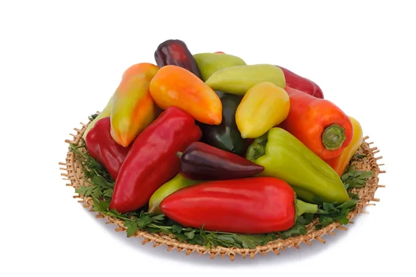 Red, yellow and green peppers on the wicker dish on a white back — Stock Photo, Image