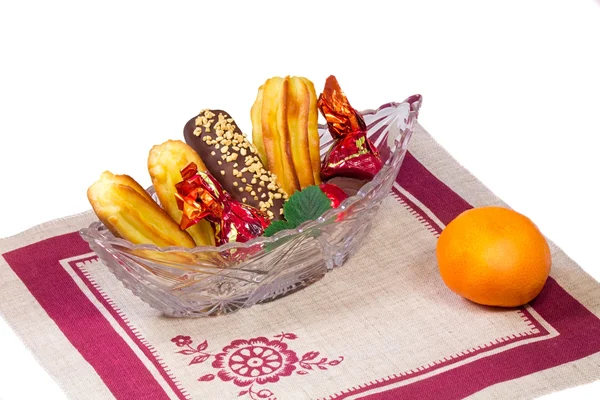 Bolos e doces em um vaso de cristal, uma tangerina, um guardanapo em um w — Fotografia de Stock