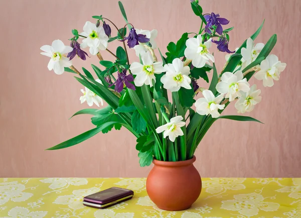 Des narcisses en fleurs dans un vase sur une table . — Photo