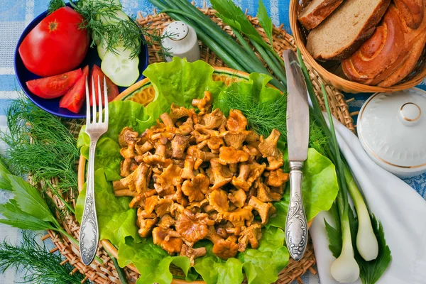 Fried mushrooms of chanterelle on a dish together with lettuce l — Stock Photo, Image