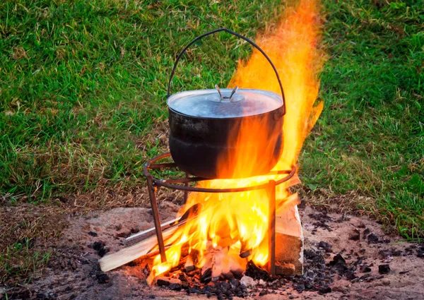 Em um fogo há uma panela na qual a comida se cozinha . — Fotografia de Stock