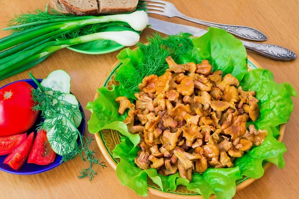 Fried mushrooms of chanterelle on a dish together with lettuce l — Stock Photo, Image