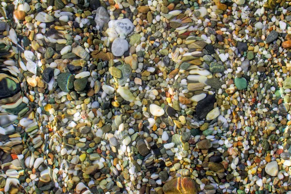Petites pierres de mer au bord de la mer, couvertes d'une vague de mer . — Photo
