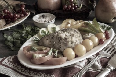 Keten peçetenin üzerindeki masada pişmiş tavuk bacağı ve sebzelerle dolu bir tabak var. Meyveler, baharatlar. Ön manzara, yakın plan..