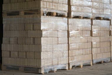 Paletlerin üzerinde baskılı çam ağacı briketleri. Yumuşak odun talaşlarından çıkan soba için katı yakıt..