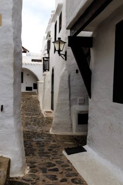 Menorca 'da eski bir beyaz köyde, kaldırım taşı sokağında dar bir sokak köşesi.