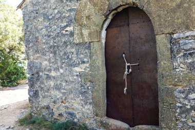Eski dövülmüş metal kapı bir iple bağlanmış ve emniyete alınmış.